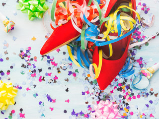 Flat lay background with woman's red pump shoes, colorful confetti, streamers. Party or sale concept.