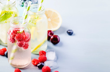 Summer drinks set. Berry, fruit and citrus non-alcoholic refreshing ice cold beverages and cocktails in glass bottles on blue background