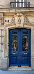Old door. Elegant antique blue door of old building in Paris France. Vintage wooden doorway and ornate fretwork stone wall of ancient house in classical architecture. Framed door panels with lattice.