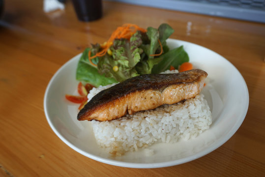 Closed up of Grilled salmon with teriyaki sauce on Japanese rice serving with fresh salad