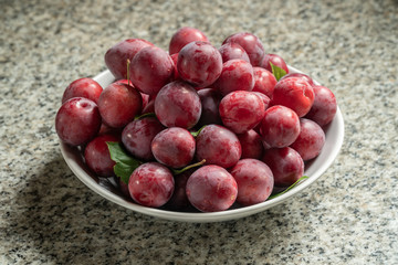 Fresh organic red plums in bowl