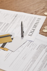 selective focus of bankruptcy form among documents, credit cards and coins on wooden table