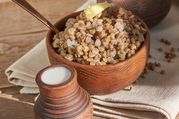 close up Buckwheat porridge with butter in a bowl on white wooden background.