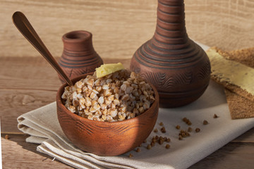 cooked buckwheat with a slice of butter served with rye crisps on wooden table.
