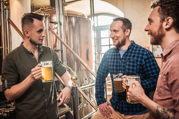 Three men tasting fresh beer in a brewery