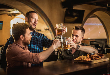 Friends drinking draft beer and watching tv in a pub