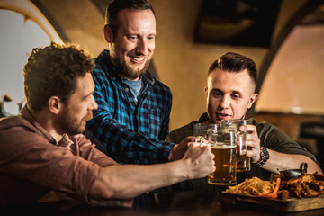 Friends drinking draft beer and watching tv in a pub