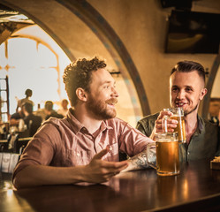 Friends drinking draft beer and watching tv in a pub