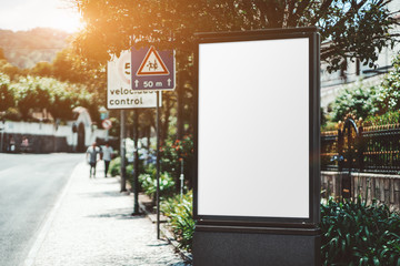 Mockup of a blank information poster in urban settings near the road; an empty vertical street...