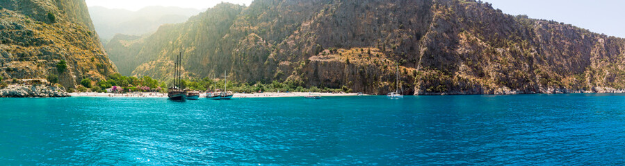 Fototapeta na wymiar Sailing ships moored in a secluded bay with turquoise water at sunrise, Oludeniz, Turkey panoramic
