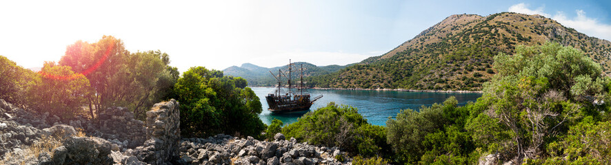 Pirate ship moored in a secluded bay with turquoise water at sunset, Oludeniz, Turkey panoramic