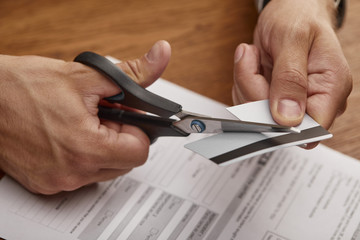 cropped view of businessman cutting credit card with scissors at wooden table