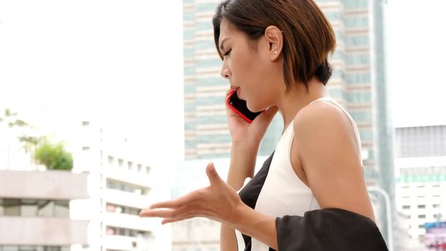 Worried upset having problems pretty asian woman talking smart phone mobile city background.