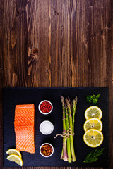 Fresh raw salmon fish served on black stone on wooden table