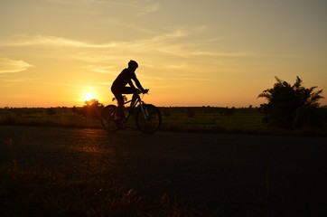 Fototapeta na wymiar silhouette of cyclist riding bike on sunset