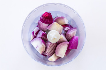 Top view of purple onions in blender on white background