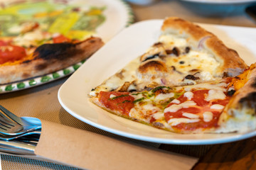 Slice of tasty italian pizza on a plate in restaurant