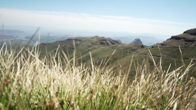 Revealing shot of the beautiful green Drakensberg mountains in South Africa from behind the grass