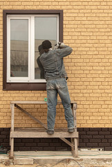The worker installs a metal window in the house