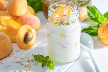 Oatmeal milkshake, smoothie or yogurt with fresh apricot on a white wooden table.
