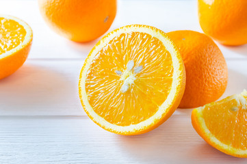 Fresh sliced and whole oranges on white wooden table.