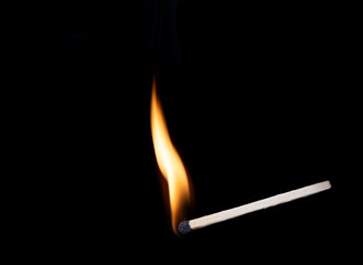 Burning wooden match over black background. Copy space