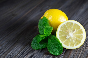 Fresh lemons and mint leaves on a dark wooden background. © Sasha Kochetkova