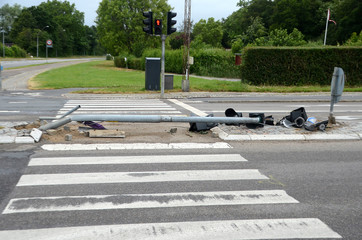 Traffic light mast has been turneed over by a truck, parts of the lamps lay around.