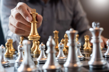 Business man take a king figure checkmate on the chess board game - strategy, management or leadership success concept.