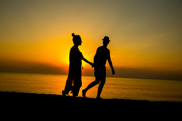 Couple on the beach with a beautiful sunset in background