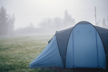 tent camp in the early foggy morning on a clearing near the forest