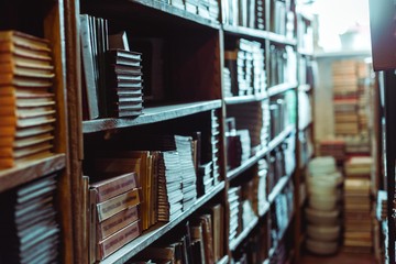 selective focus of retro books on wooden shelves in library