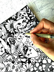 The artist draws kawaii cute animals in graphic style. Hand and liner closeup.