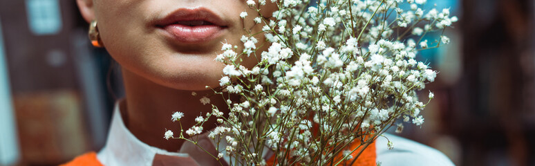 panoramic shot of young adult woman holding white flowers
