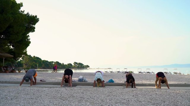 Baska Voda, Croatia - Jun 12, 2019: people stretch at yoga class on seaside