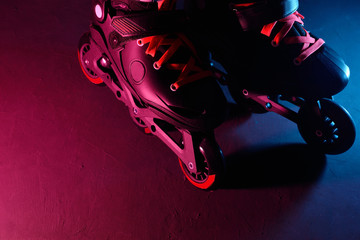 Close up view of roller skates inline skate or rollerblading on dark grunge background in neon blue...