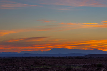 Sky colored yellow and orange above blue mountains on the horizon