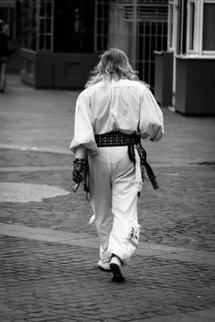 Un uomo di spalle vestito come uno sciamano cammina in una strada di Parigi 