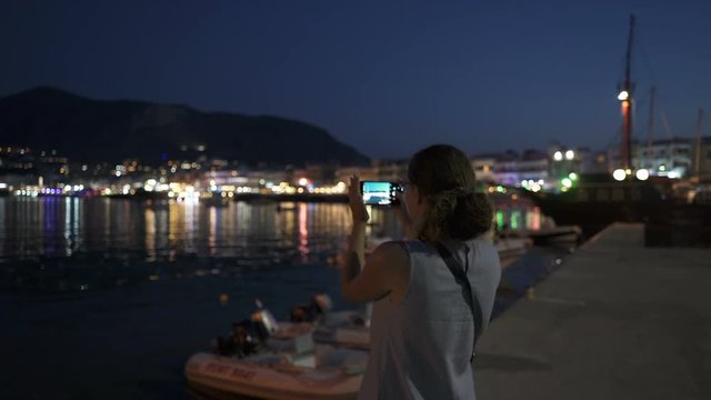 A Young Woman Photographs by Phone the Night Coast of Crete
