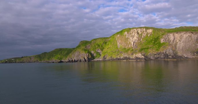 Sunset boat trip Ireland harbour green coast jagged rock cliff