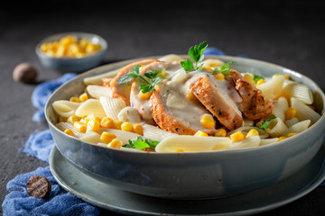 Pasta with chicken, corn and bechamel sauce on grey table
