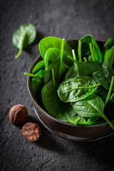 Raw green spinach in small rustic brown bowl