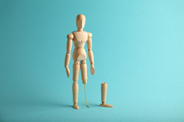 Wooden figure of man with artificial prosthetic leg. Amputee and disability concept.