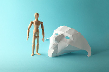 Wooden figure is an introvert - hiding behind paper mask. Closed in itself, hawto.