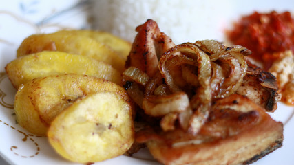 African fried chicken with fried bananas, rice, fried onions, chili sauce and candlenut sauce.