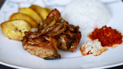 African fried chicken with fried bananas, rice, fried onions, chili sauce and candlenut sauce.