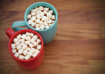Fototapeta na wymiar Two cups with cocoa drink and marshmallows on wooden table with room for text