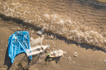 Plastic bag and bottles on the beach, seashore and water pollution concept. Trash (empty food...