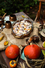 Autumn outdoor still life with pumpkin cinnamon buns in oval glass dish on wooden table
