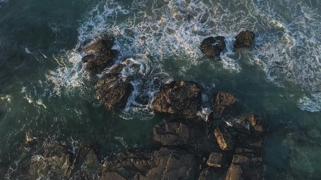 Aerial 60fps Slow motion: Playa de las Catedrales Galicia Spain at Sunset. Beach of spectacular cliffs and cracks facing Atlantic ocean. Popular touristic place